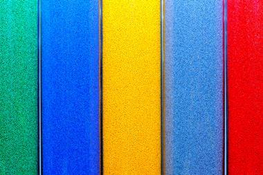 An image showing green, blue, yellow and red plastic pellets in trays