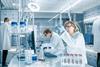 Researchers in a lab, observing blue liquid in a beaker